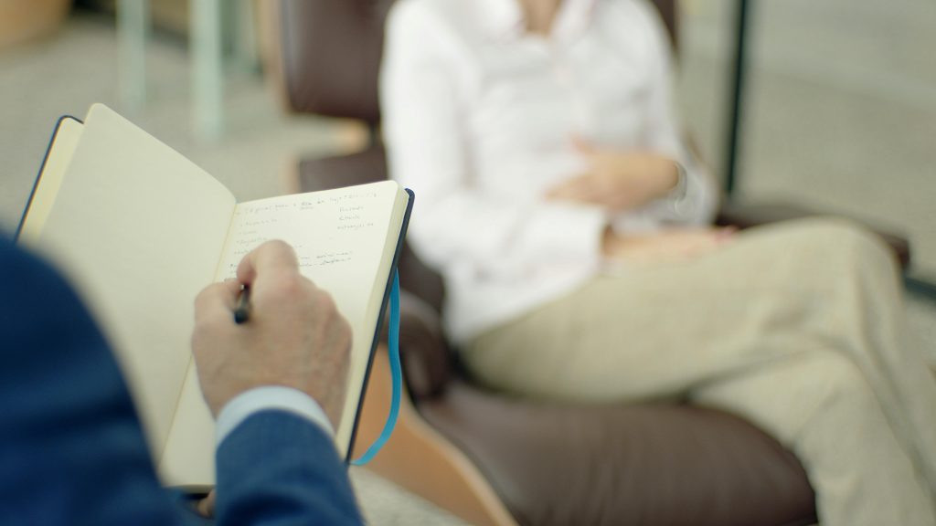 A professional taking notes in a client meeting.